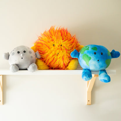 Space plushies included in the Best Seller Bundle sitting on a shelf together as a group on the wall. Soft plushies