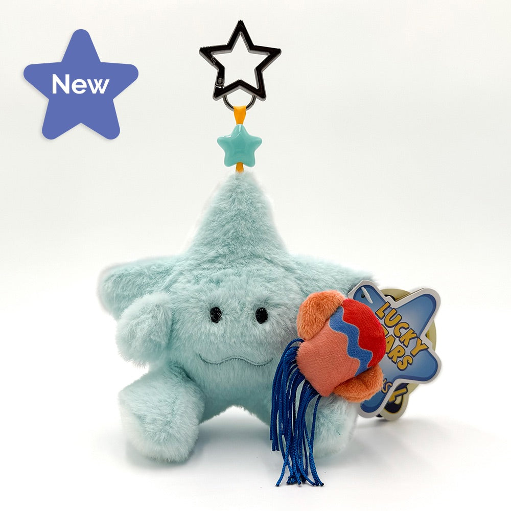 A mint green plush toy shaped like a star , holding silver cups on yellow straps, with a pink star topper - Libra- and a hangtag that reads 'LUCKY STARS'.