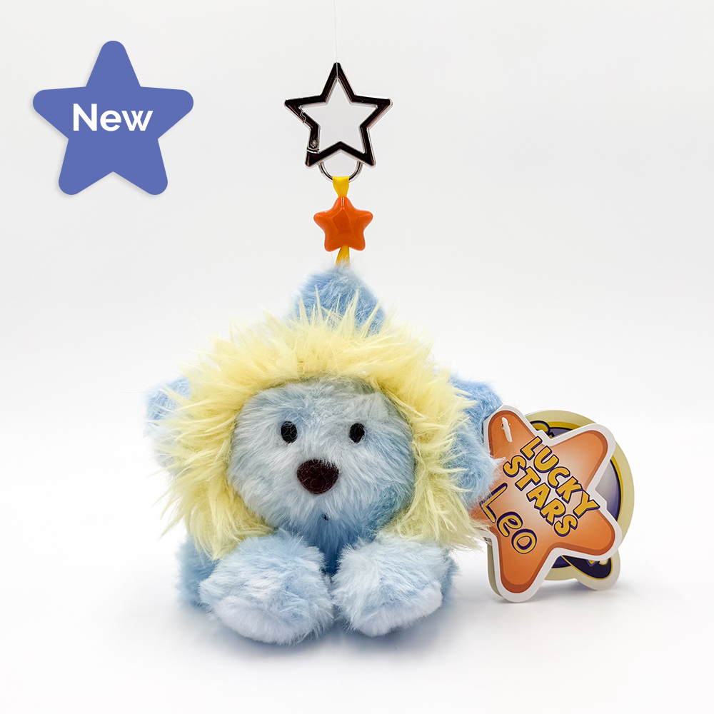 A plush lion toy in light blue and white with a fluffy yellow mane, sitting on a white background. It has a hanging star ornament above its head and a paper tag that reads 'LUCKY STARS LEO'.