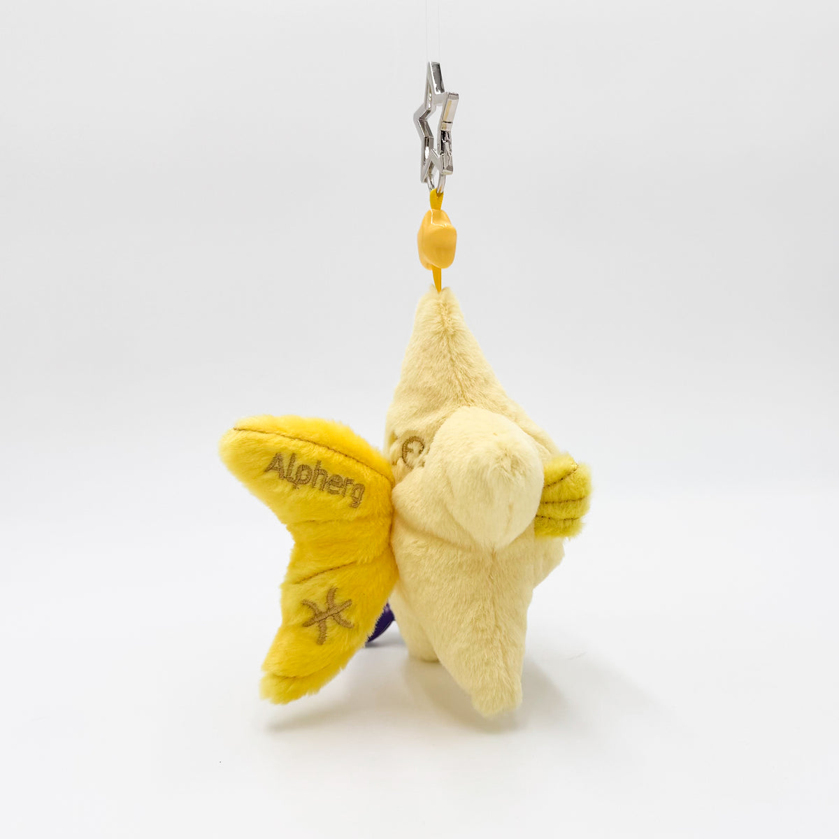 A plush star-shaped keychain charm in pale yellow and bright yellow, featuring the embroidered name 'Alpherg' and a star symbol on its wing, attached to a silver metal clasp with a yellow bead.